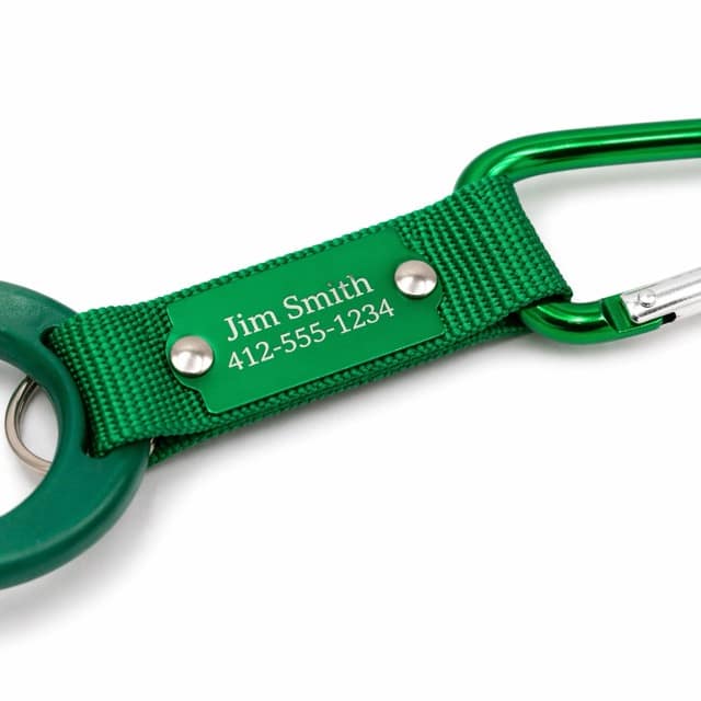 Green fabric keychain with a metal plate displaying the name 'Jim Smith' and the phone number 412-555-1234 on a green carabiner loop, close-up view.